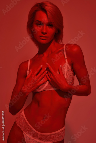 Attractive young model in lace underwear in red light studio