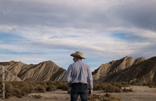 Adult man in cowboy hat standing against mountains in Tabernas desert. Almeria, Spain © WeeKwong