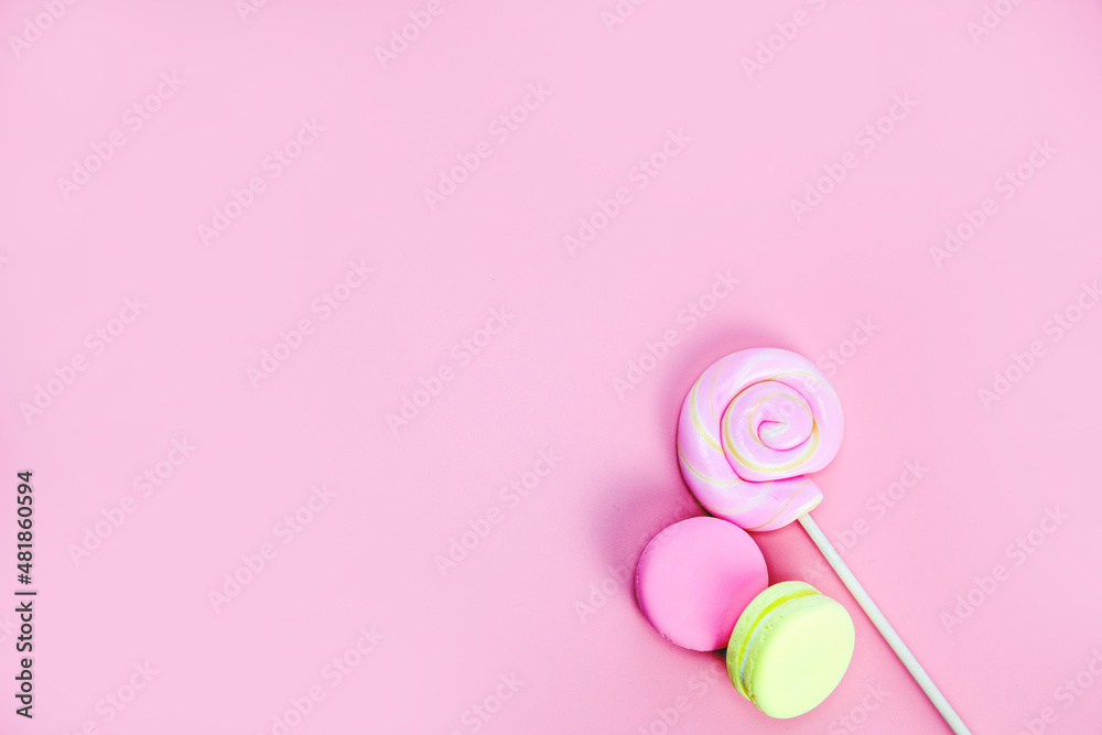 Candy sweets concept. Pink lollypop and donuts, macarons on pink background, copy space top view