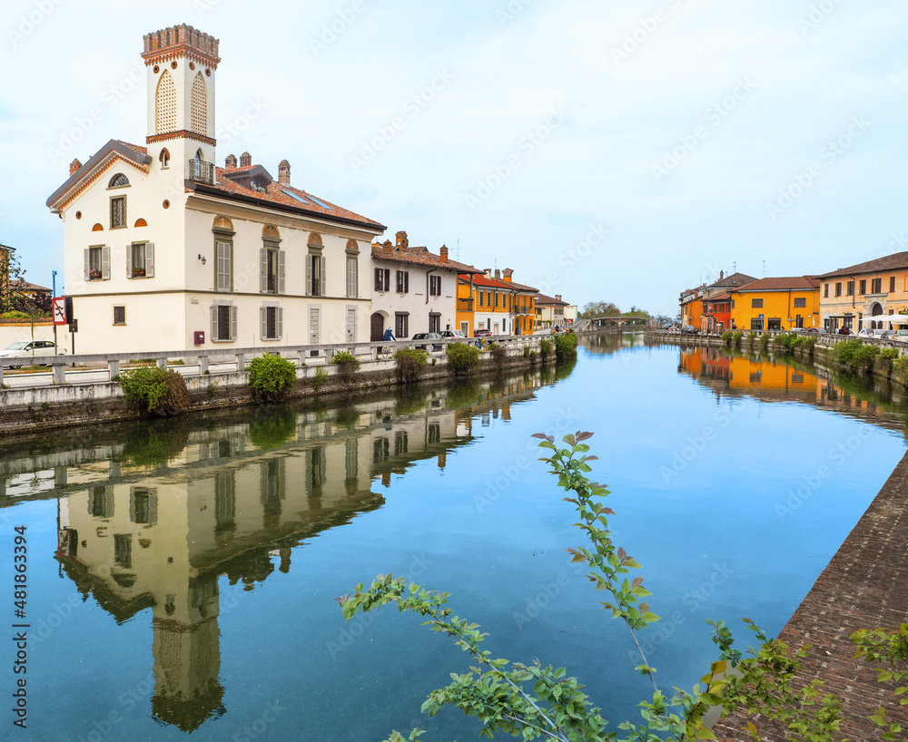 Obraz premium Colourful houses reflected in the Naviglio Grande waterway in Gaggiano, an agricultural village on the outskirts of Milan,Italy.