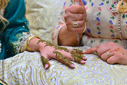 Artist applying henna tattoo on women hands. Mehndi is traditional moroccan decorative art. Close-up, top view.