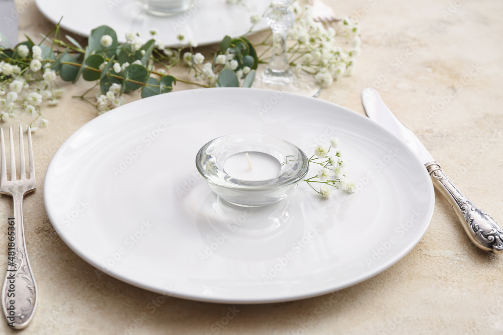 Beautiful table setting with candle and floral decor on light background, closeup