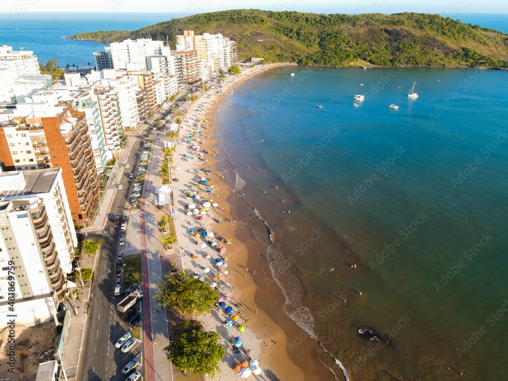 Imagem de drone da Praia do Morro em Guarapari num dia ensolarado com muitas pessoas se divertindo, aproveitando o dia na praia e praticando esportes.