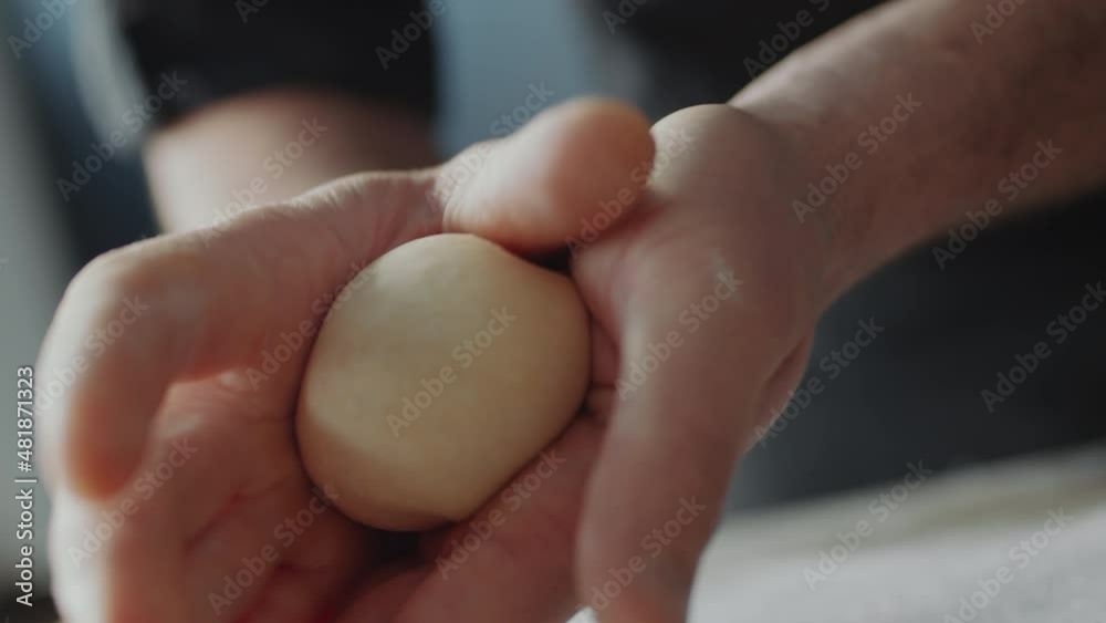 Close up shot of hands of baker shaping piece of dough in ball while preparing bun Close up shot of hands of baker shaping piece of dough in ball while preparing bun