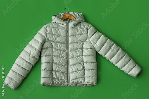 Stylish down jacket on green background