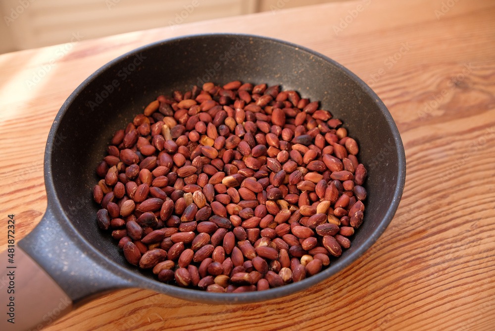Roasted peanuts in frying pan on a wooden table background. Copy space text. Roasted peanuts in frying pan on a wooden table background. Copy space text.
