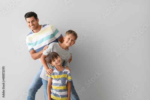 Happy man and his sons on light background photo