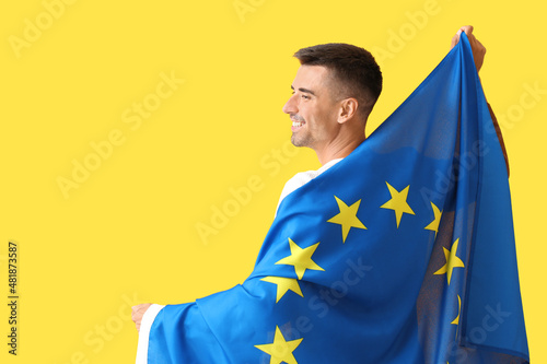 Young man with flag of European Union on color background