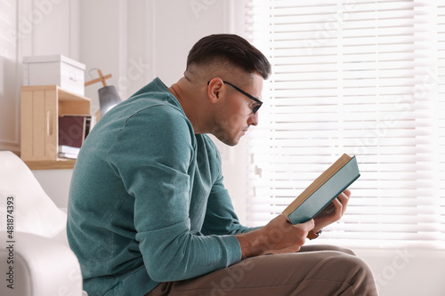 Man with poor posture reading book at home