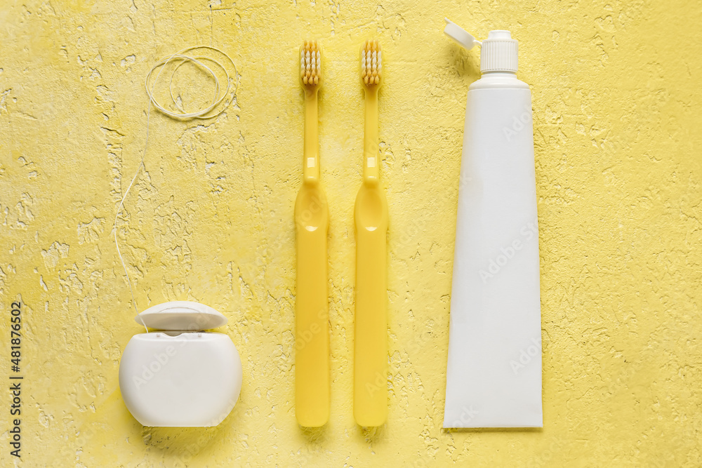Dental floss with tooth brushes and paste on yellow background Dental floss with tooth brushes and paste on yellow background