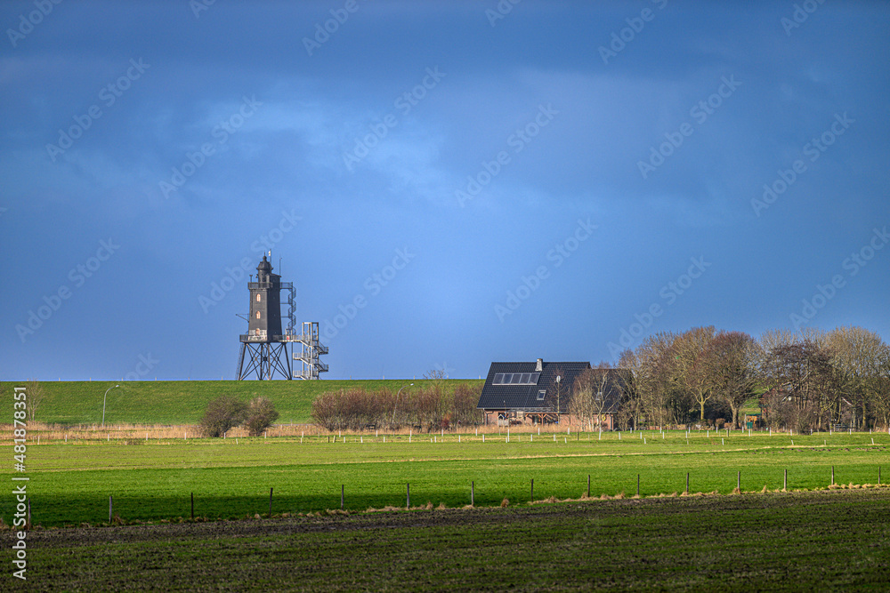 Fototapeta premium Blick aus dem Hinterland auf den Leuchtturm in Dorum-Neufeld, Niedersachsen, Deutschland