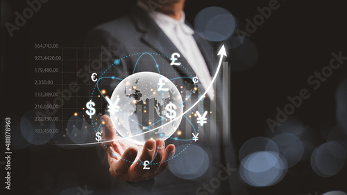A businessman hand holding a hologram globe and have a virtual line of currency flows around it and a graph showing the ups and downs of forex trading, the concept of global currency exchange.