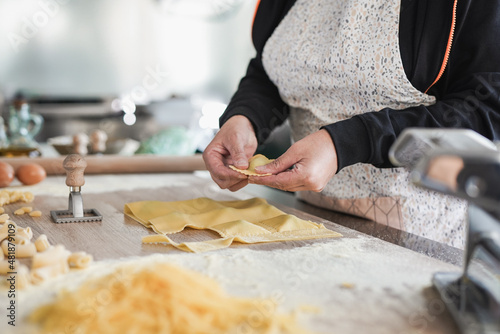 Senior woman doing fresh made ravioli inside pasta factory