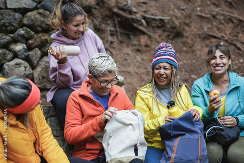Multiracial women doing a break during trekking day - Multi generational female friends in to the woods