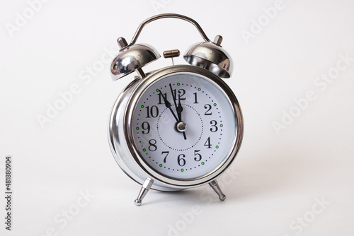 Metallic alarm clock with shadow on gray background
