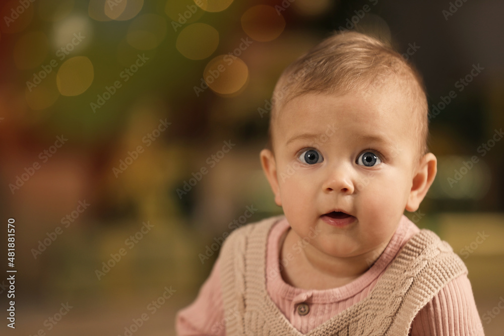 Cute little baby and blurred Christmas lights on background, space for text. Winter holiday Cute little baby and blurred Christmas lights on background, space for text. Winter holiday