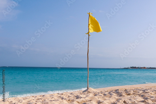 Yellow flag during a beautiful day at the beach in Cancun. 