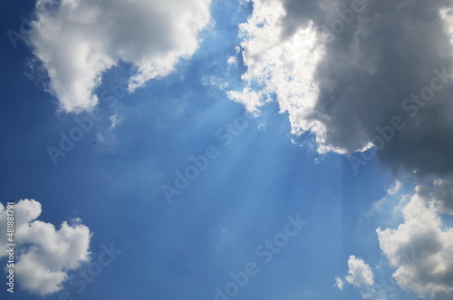 blue sky with clouds. Sunbeams shine from behind a dark cloud © SERHII