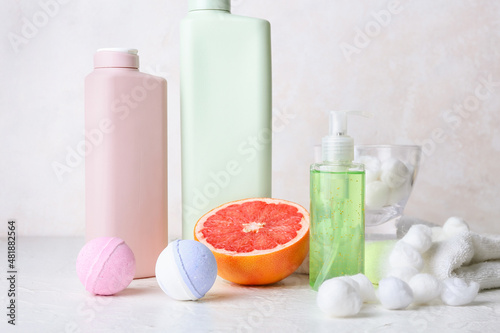 Different bath supplies and grapefruit on light background