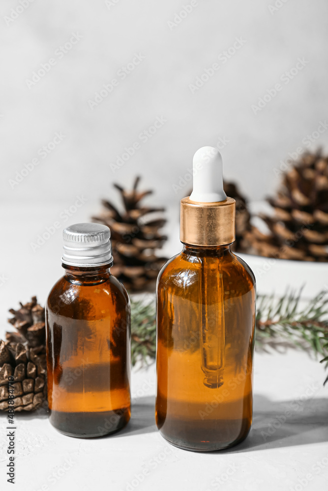 Bottles of essential oil and pine cones on light background, closeup Bottles of essential oil and pine cones on light background, closeup
