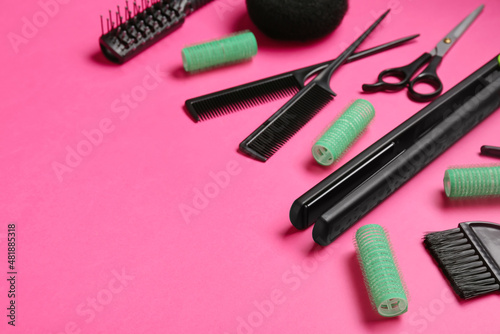 Set of hairdresser's tools and hair curlers on pink background, closeup