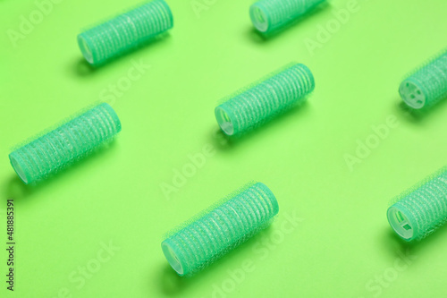 Set of hair curlers on green background