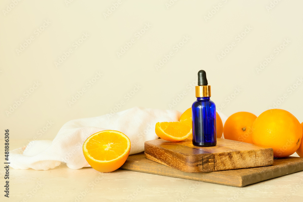 Bottle of essential oil and fresh oranges on light background Bottle of essential oil and fresh oranges on light background