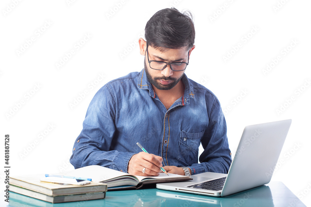 young businessperson writing on notepad or diary while working on laptop or computer young businessperson writing on notepad or diary while working on laptop or computer