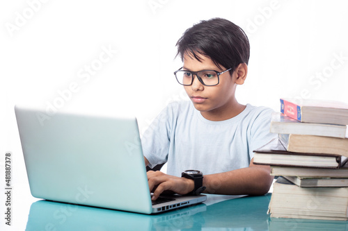 smart child using laptop for online education with some books on desk