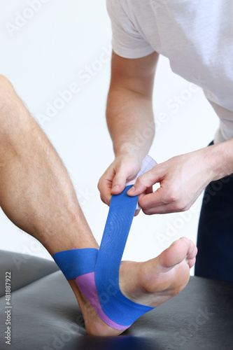 Картината върху платно Kinesiology taping treatment with blue tape on male patient injured foot
