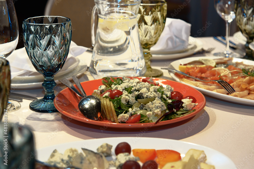 Table setting with appetizers, dishes, salads, glasses and jug of water. Selective focus. Table setting with appetizers, dishes, salads, glasses and jug of water. Selective focus.