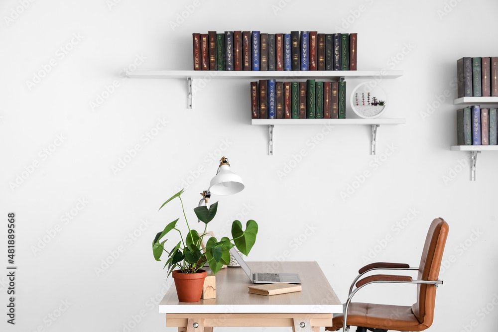 Table and books on shelves hanging on wall in interior of room