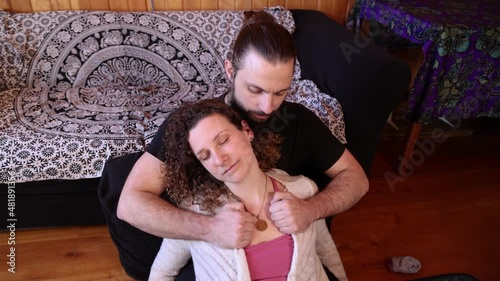 Close up footage during a spiritual tantra session, as a relaxed woman is seen in the arms of a muscular man using traditional Shiatsu techniques.