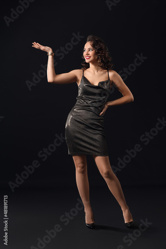 Elegant woman in evening dress posing on dark background