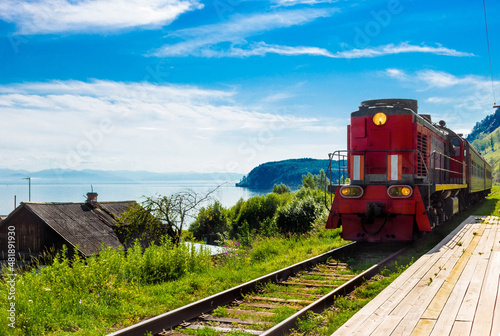 Obraz na płótnie Landscape for travel with the arrival of a red train on a wooden deserted platform Circum-Baikal railway in a village on Lake Baikal in a bright summer sunny day