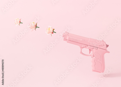 Fotografering Pink gun and three rose flowers bullets against pastel pink background