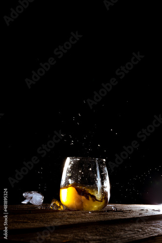 vaso de whisky con cubitos de hielo sobre fondo negro