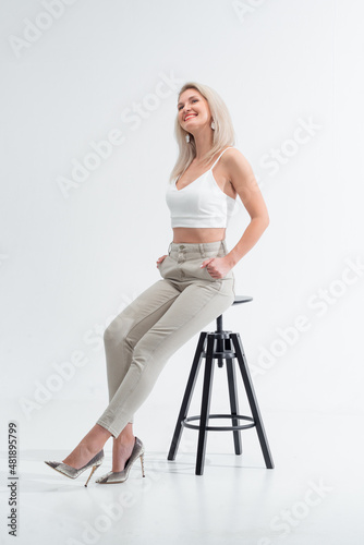 Beautiful blonde in jeans in the studio on a light background.