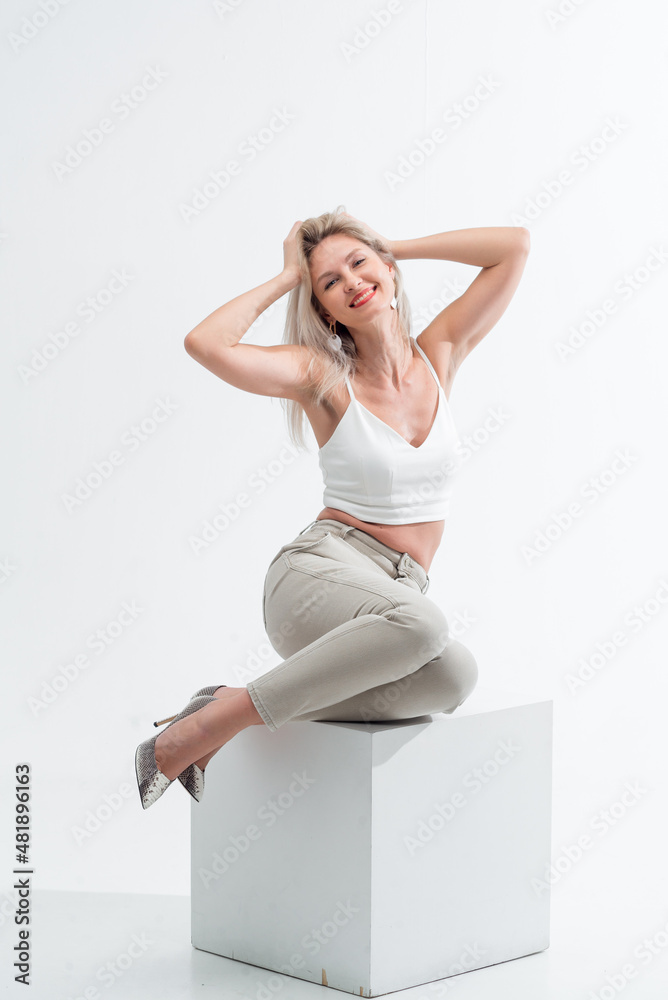 Beautiful blonde in jeans in the studio on a light background.