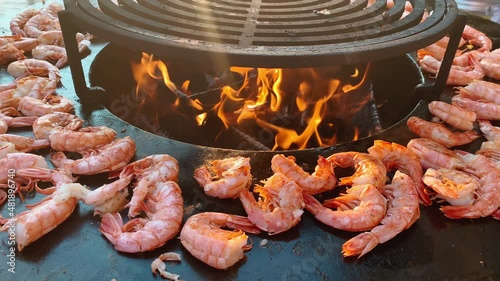 Close up footage of process of grilling fresh king prawns on brazier with hot flame at summer days, a hand in rubber gloves lays out king prawns on a hot iron surface, fresh seafood, photo