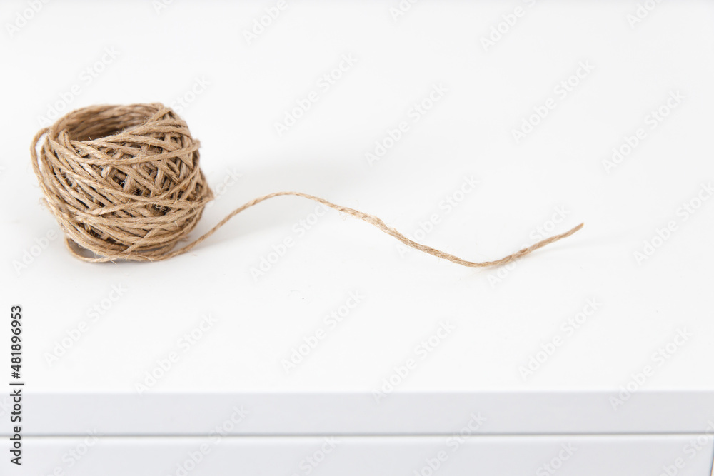A skein of craft twine on a white chest of drawers. A skein of craft twine on a white chest of drawers.