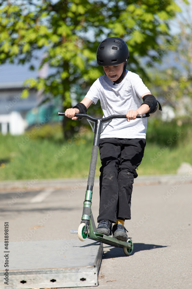 The boy jumps on a scooter.