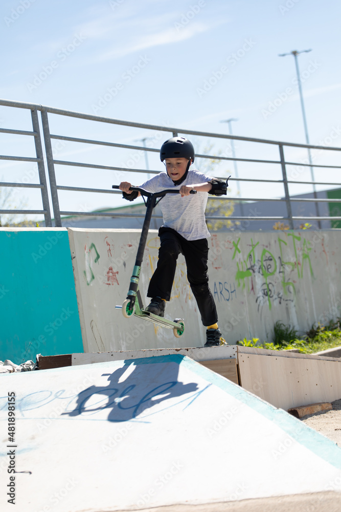 The boy jumps on a scooter.