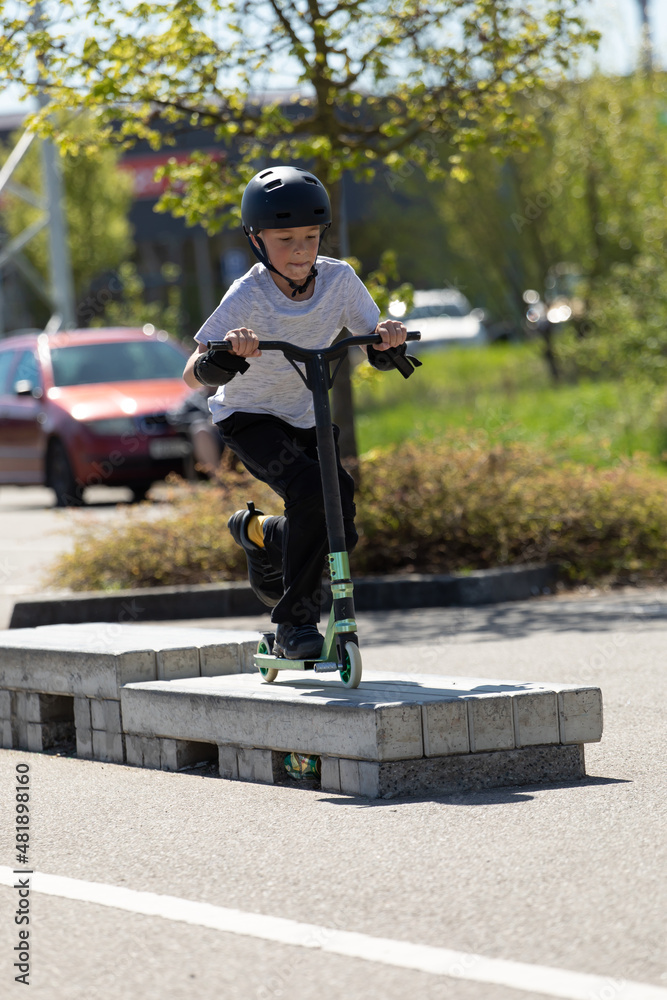 The boy jumps on a scooter.
