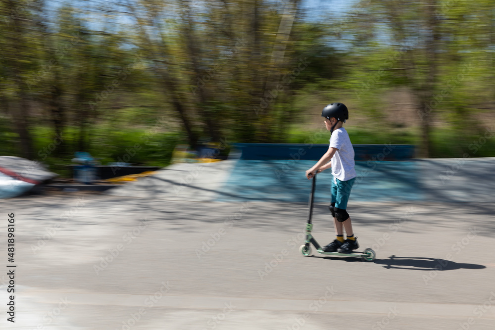 The boy jumps on a scooter.