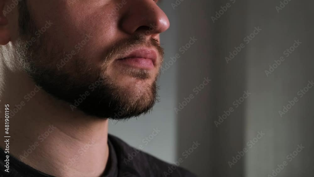 Close-up of a bearded athletic man drinking a sports supplement from a shaker in a dark room Close-up of a bearded athletic man drinking a sports supplement from a shaker in a dark room