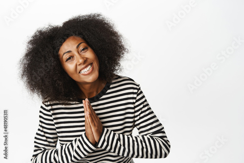 Portrait of happy smiling african american woman holding hands in namaste, pray pose, powing and say thank you, express gratitude, standing over white background