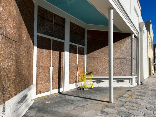 Fényképezés A boarded up storefront with an abandoned yellow shopping cart