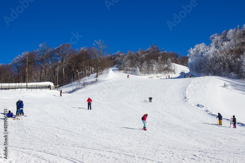 People snowboarding downhill in the ski trails. People skiing and snowboarding freestyle in the ski resort. Winter sports leisure activities. Extreme sports concept. Snow activities concept. 