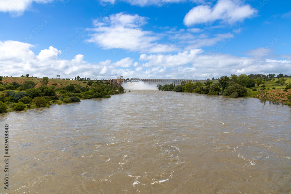 Vaal River in flood with the open Sluice gates  and dam wall of the Vaaldam in South Africa after good rains in the background